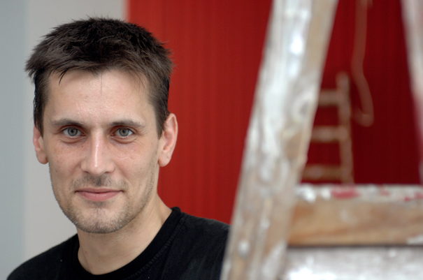 Ein Mann steht neben einer Leiter mit Farbklecksen 