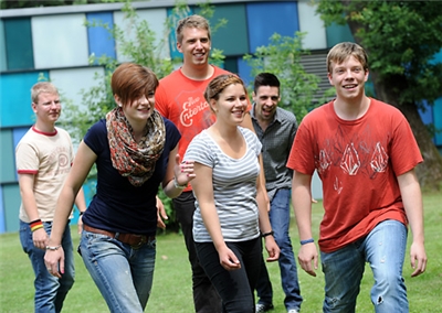 Gruppe Freiwilliger  Gruppe Freiwilliger spielt Fangen auf dem Rasen