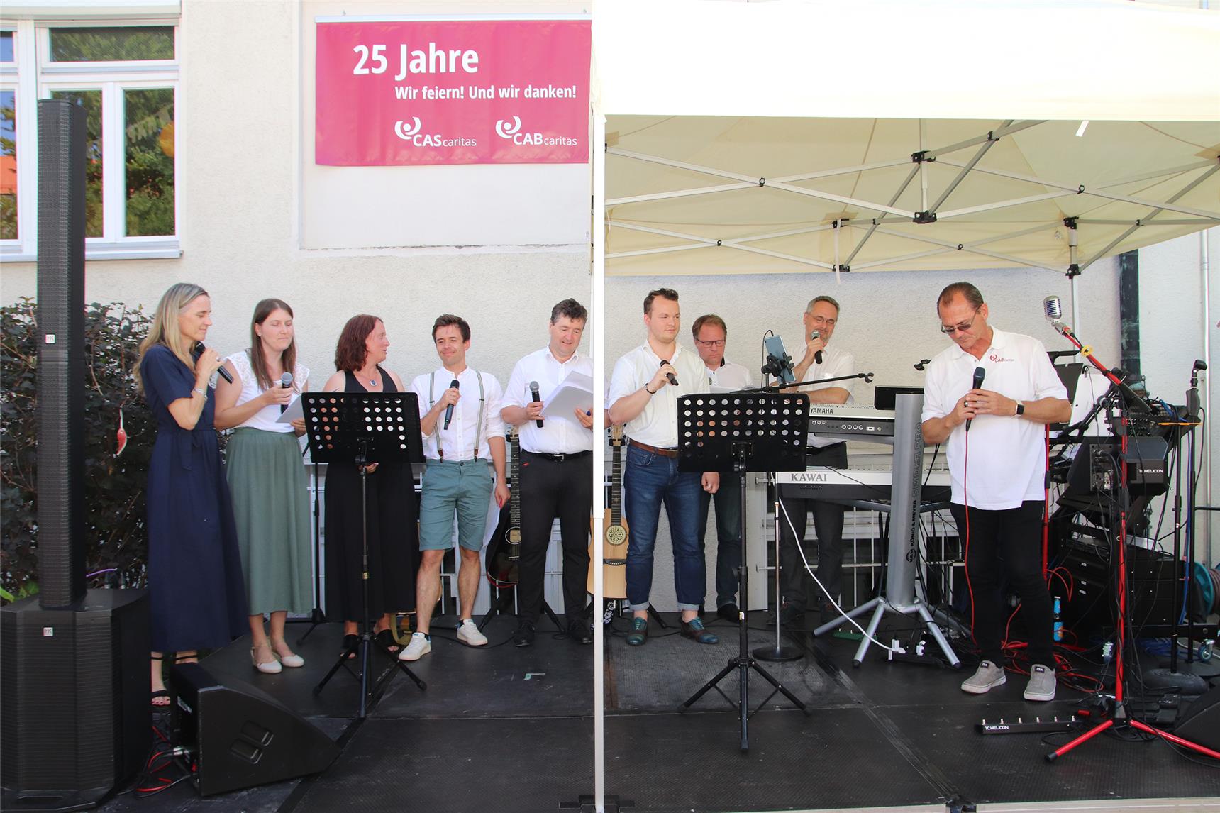 Frauen und Männer der CAB Caritas Augsburg Betriebsträger gGmbH und der CAS Caritas Solidarwerk singen auf der Bühne. 