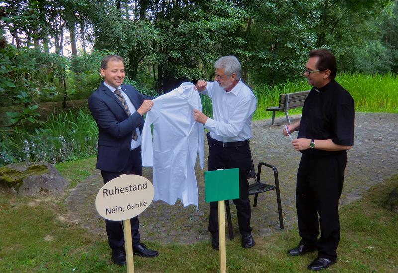 Caritas-Abteilungsleiter Stefan Schmidberger (links) und Caritasdirektor Dr. Roland Batz (rechts) übergeben symbolisch einen Arztkittel an Dr. Reinhard Legner (Bildmitte). Von Ruhestand möchte der 65-jährige Arzt nichts wissen.